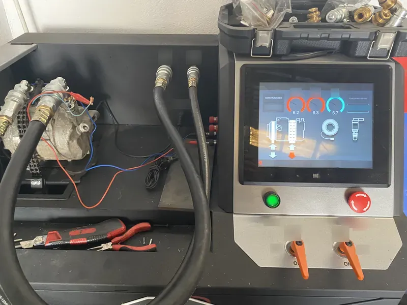 La máquina de carga del aire acondicionado del taller, con mangueras y pantalla.